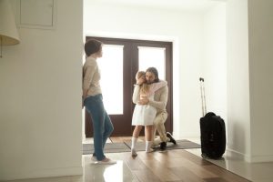 Little kid girl embracing dad leaving family moving out with travel case